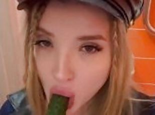 A baby with bare tits plays with a cucumber and sucks it with her mouth.